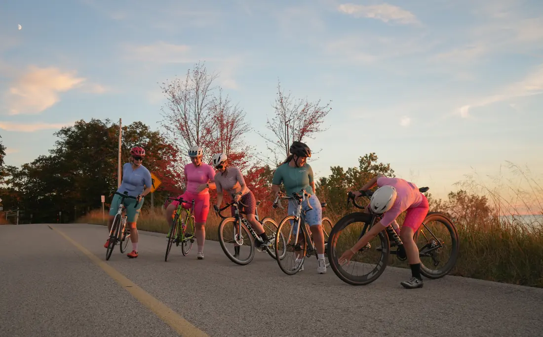 A group of five riders checking their bikes at sunset