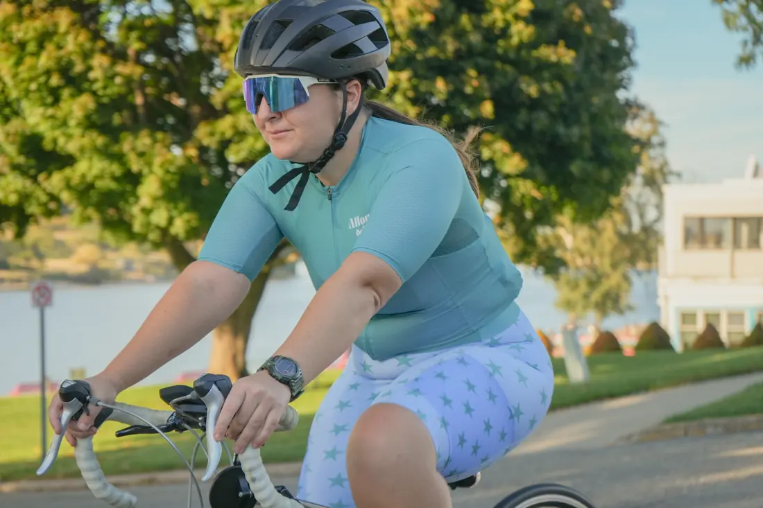 A rider in the teal jersey and star-print bibs on a lakefront road