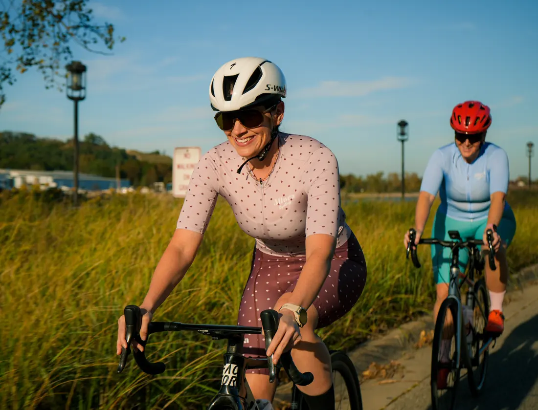 A rider in the dusty-rose kit with riders in blue, pink and teal behind her