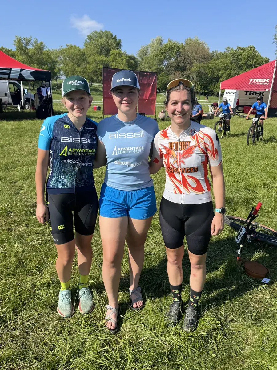 Three women smiling together at a race, two of them in Bissell Advantage Benefits Group kit